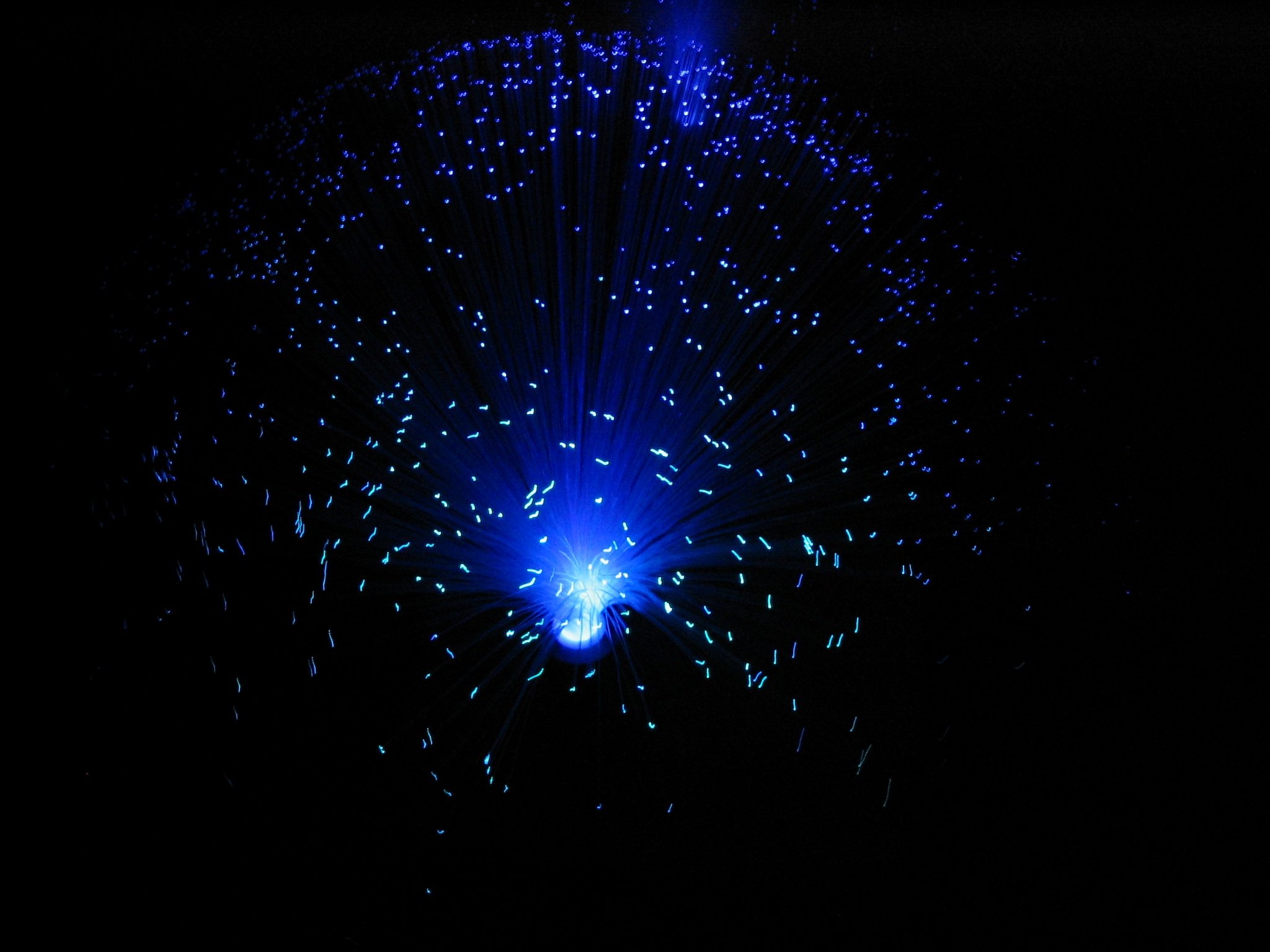 Illuminated fiber optic strands glowing blue against black